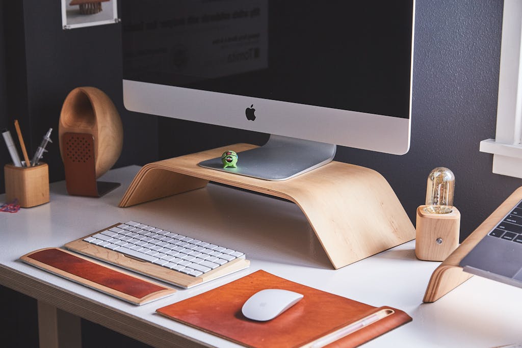 Sleek modern home office desk with computer, wooden accessories, and organized workspace.
