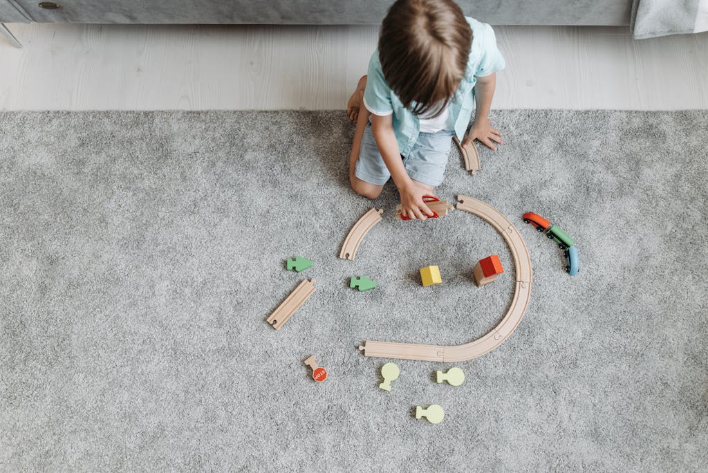 A child playing with a colorful toy train set on a living room carpet.