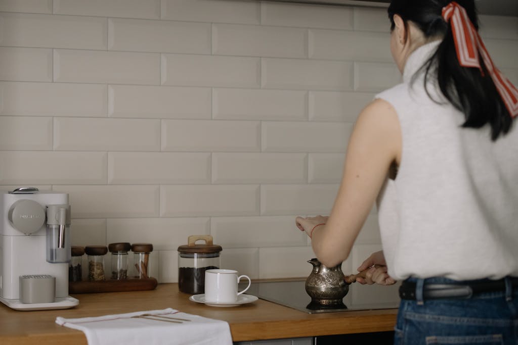 A woman making coffee in a modern kitchen with ceramic and wooden kitchenware.