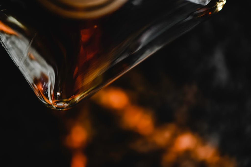 A close-up of a whiskey bottle, highlighting amber hues against a dark background.