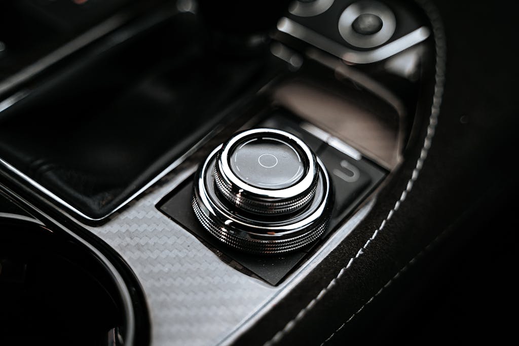 Detailed close-up image of a chrome car control button on a textured dashboard.