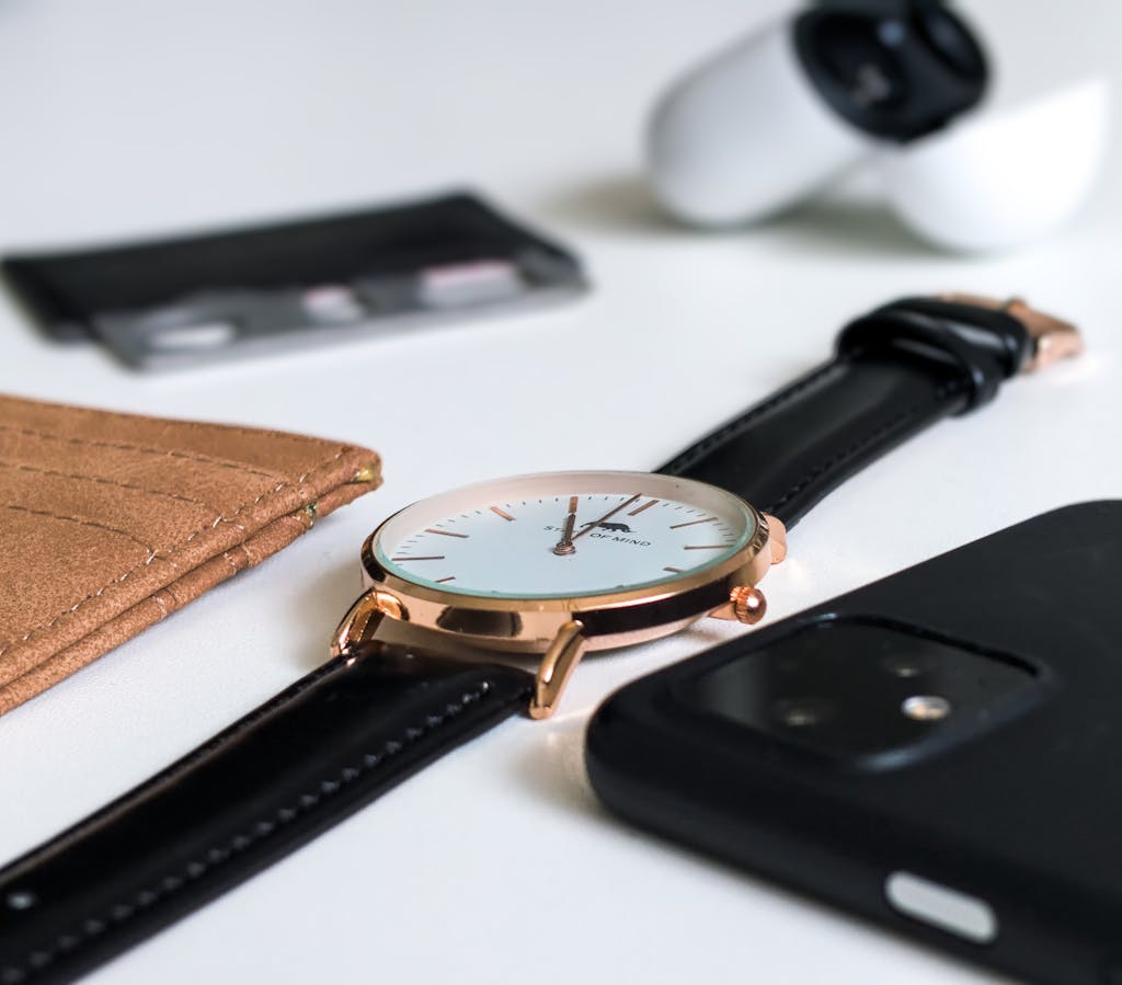 A stylish wristwatch paired with a smartphone and wallet, showcasing modern elegance.