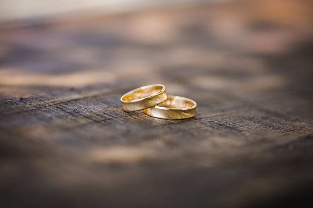 Close-up of two gold wedding rings placed on a rustic wooden surface, symbolizing eternal love and commitment.