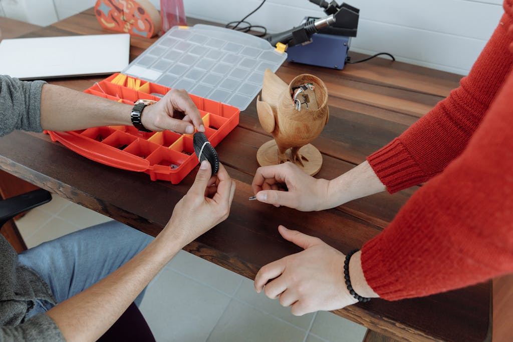 Hands working on an electronic project in a creative workshop with tools and wooden models.