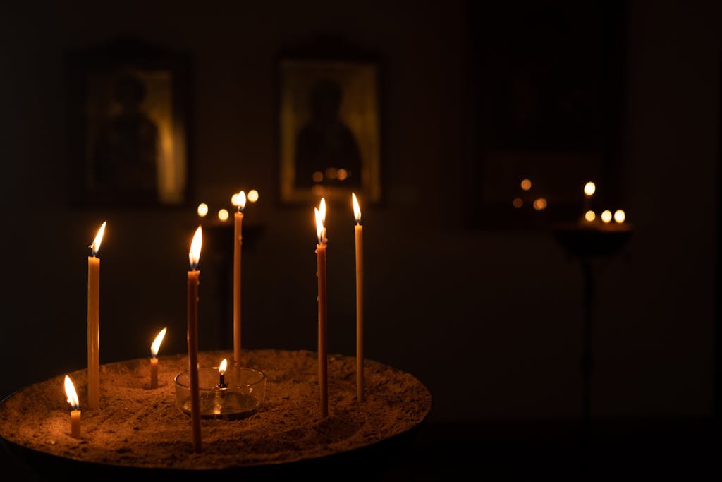 Candles illuminating orthodox icons in a dimly lit church setting, creating a warm atmosphere.