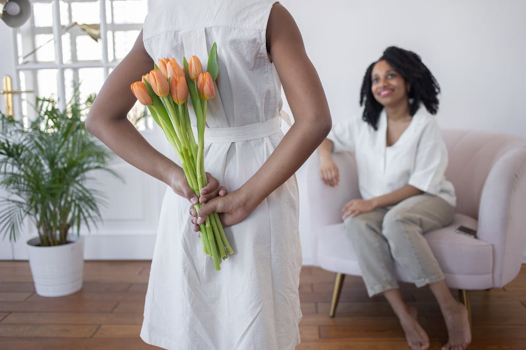 A child surprises their mother with tulips indoors, depicting warmth and love.