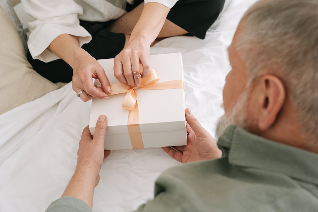 A couple sharing a gift box tied with an orange ribbon, highlighting intimacy and thoughtfulness.