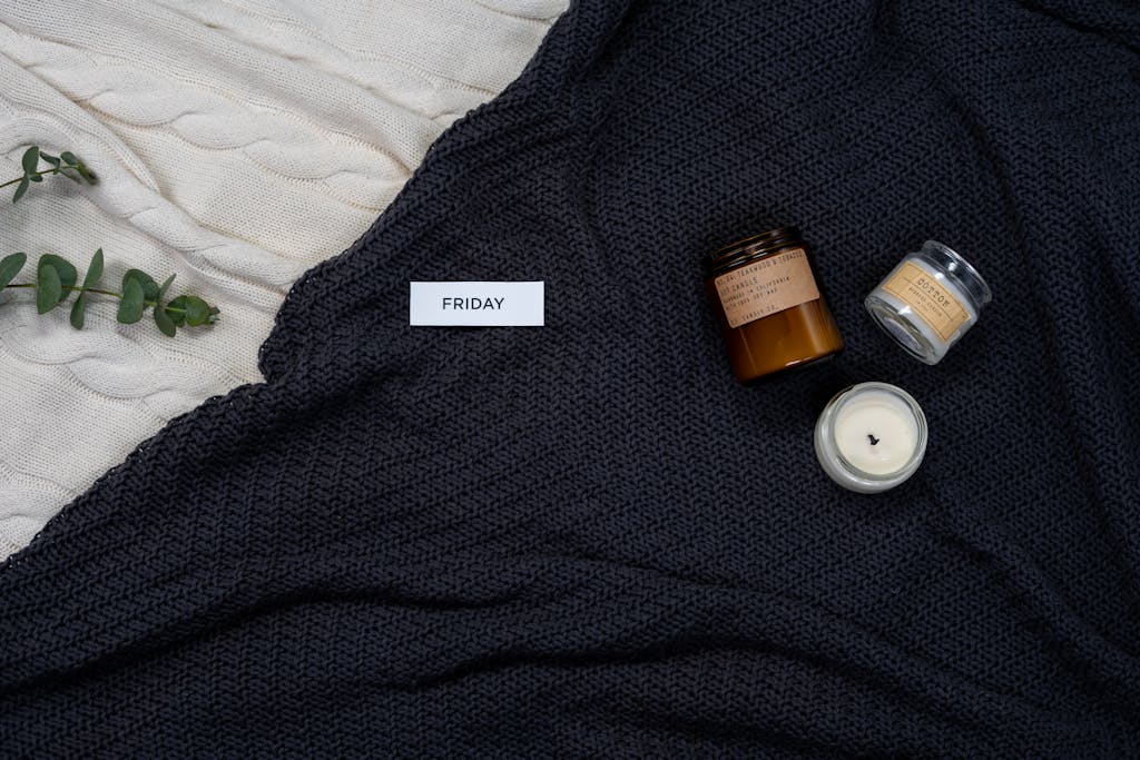 Warm knitted blankets with candles and eucalyptus for a cozy Friday ambiance.